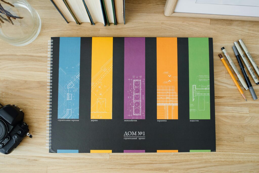 Design and architecture workbook with colorful blueprints on a wooden desk.