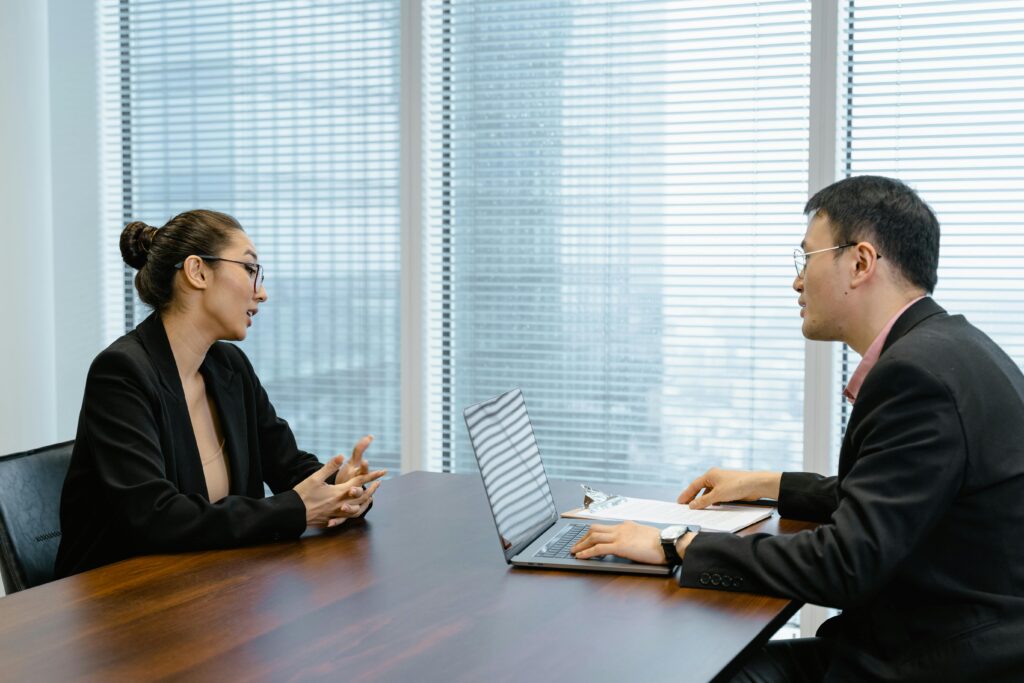 Two colleagues in a professional meeting discussing business strategy at an office table.